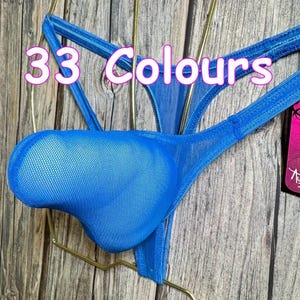 May include: A close-up of a blue thong-style undergarment with a mesh pouch. The text "33 Colours" is displayed in pink and white. The undergarment is suspended on a gold-colored hanger against a wooden background.