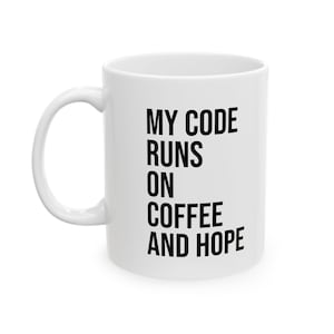 Puede incluir: Taza de café de cerámica blanca con texto negro que dice "My code runs on coffee and hope".