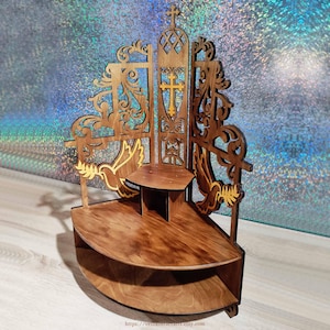 Puede incluir: Estantería de esquina de madera con temática religiosa. La estantería presenta intrincados diseños recortados, incluyendo una cruz, palomas y adornos ornamentados. La madera tiene un tinte marrón cálido y la estantería tiene múltiples niveles para exhibir.