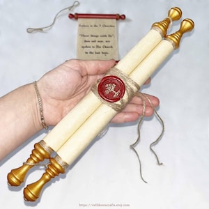 May include: Two parchment scrolls tied with twine and sealed with a red wax stamp. The scrolls have gold-painted finials. A small scroll with text is in the background. The text on the small scroll reads "Letters to the 7 Churches".