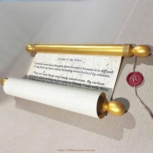 Może przedstawiać: Zwój z kremowego papieru z czarnym nadrukiem zatytułowanym A Letter to My Father, przymocowany do dwóch złotych drewnianych drążków z zaokrąglonymi końcami. Czerwona pieczęć lakowa z literą R jest przymocowana do zwoju cienkim sznurkiem.