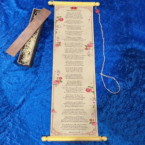 Può includere: Una pergamena beige con una poesia e decorazioni floreali, arrotolata su tasselli di legno gialli. Il testo recita "Buon Compleanno, [Nome]" con una grafica a corona. Sullo sfondo c'è una scatola di legno con paglia.