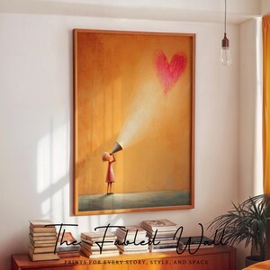 May include: Framed art print featuring a child holding a megaphone, projecting light towards a red heart. The artwork is set against an orange background. The text "The Fabled Wall" and "PRINTS FOR EVERY STORY, STYLE, AND SPACE" are at the bottom.