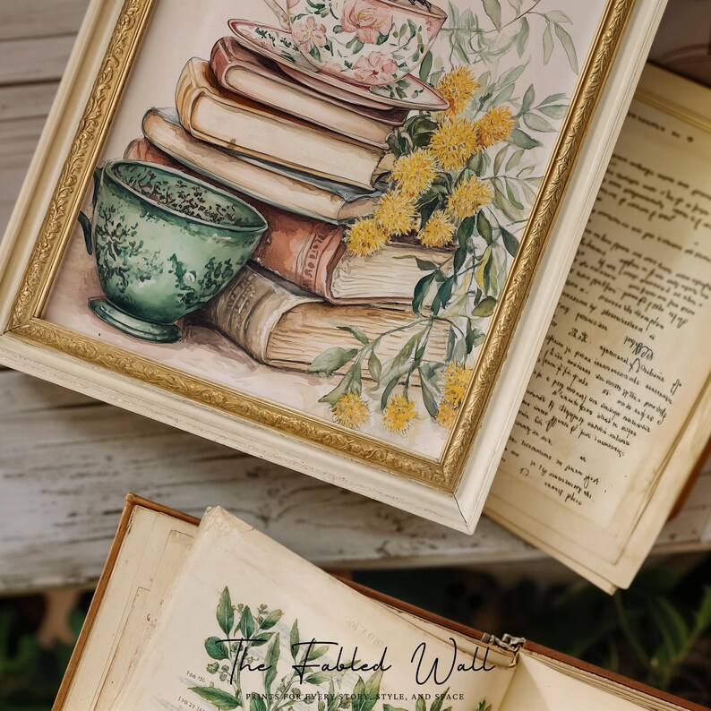 Pu&ograve; includere: Una stampa ad acquerello incorniciata con una pila di libri, tazze da t&egrave; e fiori gialli. La stampa ha una cornice color crema con finiture dorate. Una tazza da t&egrave; verde &egrave; in primo piano.