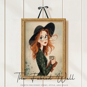 May include: Framed art print featuring a red-haired woman wearing a black hat and glasses, holding a book and a mug. The print is in a gold frame and is suspended by a green ribbon. The text "The Fabled Wall" and "PRINTS FOR EVERY STORY, STYLE, AND SPACE" are at the bottom.