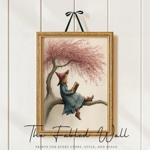 May include: A framed print depicting a child reading beneath a pink flowering tree. The child is dressed in a blue dress and a pointed hat. The gold frame is hung by a green ribbon. The text "The Fabled Wall" is at the bottom.