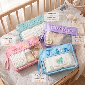 Pode incluir: Quatro bolsas retangulares com frente transparente e bordas de tecido nas cores menta, roxo, rosa e azul. Cada bolsa apresenta um nome personalizado em letras texturizadas em relevo e contém diversos itens de bebê, como fraldas e lenços.