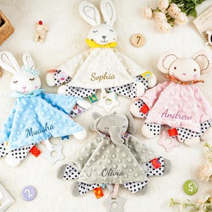 Puede incluir: Cuatro mantitas de seguridad de peluche con cabezas de animales, incluyendo dos conejos, un rat&oacute;n y un elefante. Cada manta tiene una textura con relieve, una parte inferior de lunares blancos y negros, un mordedor en forma de estrella y los nombres bordados Sophia, Andrew, Muasha y Olivia.