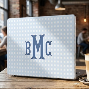 May include: A laptop skin featuring a light blue and white checkered grid pattern. Centered on the surface is a large, dark blue monogram with the letters BMC in a decorative serif font. The skin covers the back of a closed laptop computer.