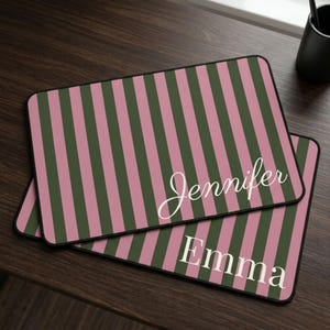 Peut inclure: Deux tapis de souris rectangulaires avec un motif à rayures verticales alternant des tons rose poudré et vert olive foncé. L'un affiche le prénom Jennifer en écriture cursive blanche, l'autre le prénom Emma en lettres blanches à empattement.