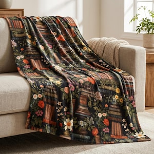 Peut inclure: Une couverture d&eacute;corative sur un canap&eacute;. La couverture pr&eacute;sente un fond sombre avec un motif de fleurs et de biblioth&egrave;ques dans des tons orange, rose, jaune et vert. La couverture est faite d'une mati&egrave;re douce.