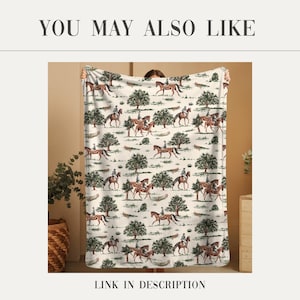May include: A cream-colored blanket featuring a repeating pattern of riders on horseback and trees. The blanket has the text "YOU MAY ALSO LIKE" at the top and "LINK IN DESCRIPTION" at the bottom.