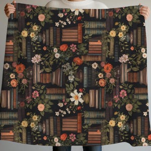 Peut inclure: Une couverture noire avec un motif r&eacute;p&eacute;t&eacute; de vieux livres et de motifs floraux. Le motif comprend des piles de livres de diff&eacute;rentes tailles et couleurs, entrecoup&eacute;es de roses, de marguerites et d'autres fleurs dans des tons d'orange, de rose et de blanc.