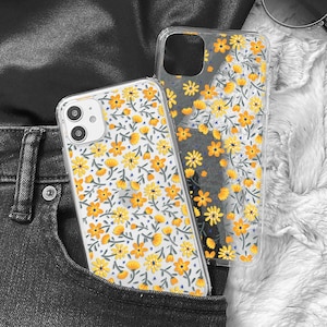 May include: Two clear phone cases with a floral pattern in yellow and white. The cases are in a jean pocket.
