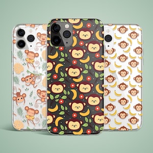 May include: Three phone cases with monkey and banana patterns. One case has a black background with red flowers, bananas, and monkey faces. The other two cases have white backgrounds with monkeys and bananas. The cases are made of clear plastic.