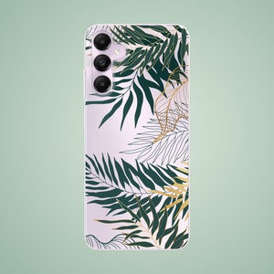 Puede incluir: Una funda de teléfono blanca con un diseño de hojas tropicales. Las hojas son verdes y doradas y tienen un contorno detallado. La funda del teléfono tiene un triple objetivo de cámara.