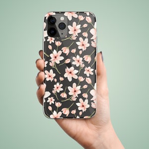 May include: A clear phone case with a black background and a pink floral pattern. The case is designed for an iPhone.