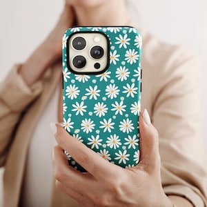 May include: A teal smartphone case featuring a repeating pattern of white daisies with yellow centers. The case has a rectangular cutout at the top left corner for the camera lenses and is designed to fit a smartphone with a triple camera system.