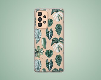 May include: A clear phone case with a beige background and a pattern of green and white leaves. The case has a cutout for the camera lens.