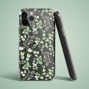 May include: A clear phone case featuring a floral pattern of green leaves and white flowers. The case is designed for an iPhone with a triple camera lens.