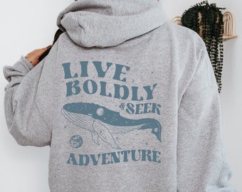 Peut inclure: Sweat-shirt à capuche gris avec un graphique de baleine bleue et le texte "Live Boldly & Seek Adventure".
