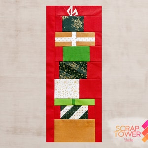 May include: A rectangular fabric quilt block featuring a vertical stack of colorful gift boxes in shades of red, green, gold, and white with various patterns including snowflakes and stars. The text SCRAP TOWER Studio is visible in the corner.
