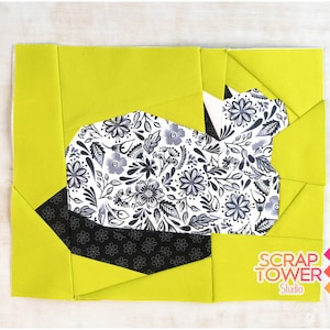 Pode incluir: Um bloco de colcha com um tecido de estampa floral em preto e branco em forma de coelho, rodeado de tecido verde limão.