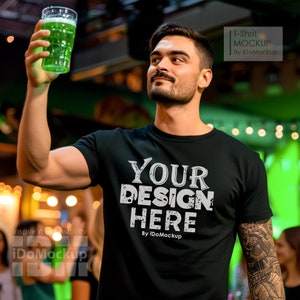 May include: A black t-shirt with the text "YOUR DESIGN HERE" in white lettering. The shirt is being worn by a person holding a glass of green liquid.