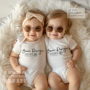 May include: Two babies wearing white onesies with the text "Your Design Here" and sunglasses. The babies are sitting on a white fluffy surface.