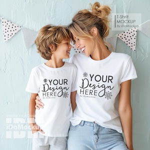 Puede incluir: Una madre y un hijo vistiendo camisetas blancas con el texto "YOUR DESIGN HERE" y un pequeño gráfico de flores. El texto va seguido de "By iDoMockup".
