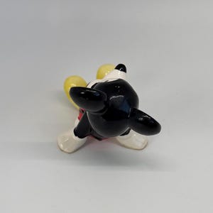 Puede incluir: Una figura de cer&aacute;mica de Mickey Mouse, vista desde arriba. La figura tiene cabeza y orejas negras, cara blanca y un atuendo rojo y blanco. Se ven las manos amarillas de la figura.