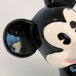 Puede incluir: Primer plano de una figura de cer&aacute;mica de Mickey Mouse en blanco y negro. La figura tiene un acabado brillante, con orejas, ojos y nariz negros. La cara es blanca con ojos negros y boca rosa. La figura es un personaje de dibujos animados cl&aacute;sico.
