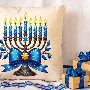 Op de afbeelding: Een wit kussen met een blauwe en gouden menorah met negen brandende kaarsen. De menorah is versierd met een blauwe strik met gouden sterren. Het kussen is perfect voor Chanukka.