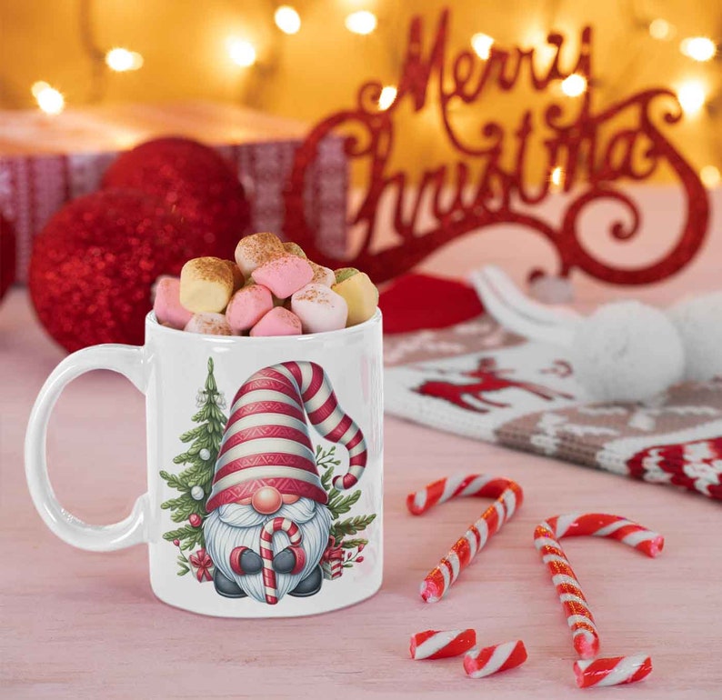 May include: A white ceramic mug filled with marshmallows, featuring a Christmas gnome design with a red and white striped hat and a candy cane. The mug is surrounded by candy canes and festive decorations.