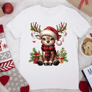 Pode incluir: Camiseta branca com uma rena de desenho animado usando um chap&eacute;u de Papai Noel e uma echarpe xadrez vermelha e preta. A rena est&aacute; cercada por luzes de Natal, presentes e bengalas de doces.