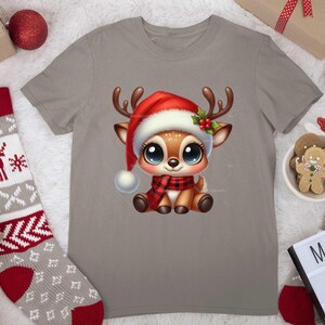 Op de afbeelding: Een grijs T-shirt met een schattig cartoon rendier dat een rode kerstmanmuts en een rood-zwarte sjaal draagt. Het rendier heeft grote bruine ogen en een rode neus. Het T-shirt is perfect voor de kersttijd.