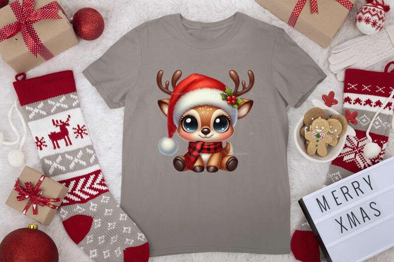 Op de afbeelding: Een grijs T-shirt met een schattig cartoon rendier dat een rode kerstmanmuts en een rood-zwarte sjaal draagt. Het rendier heeft grote bruine ogen en een rode neus. Het T-shirt is perfect voor de kersttijd.