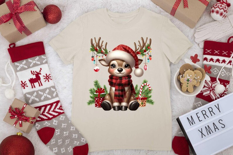 Pode incluir: Uma camiseta bege com uma rena de desenho animado usando uma echarpe xadrez vermelha e preta e um chap&eacute;u de Papai Noel. A rena est&aacute; cercada por luzes de Natal, presentes e bengalas de doces.
