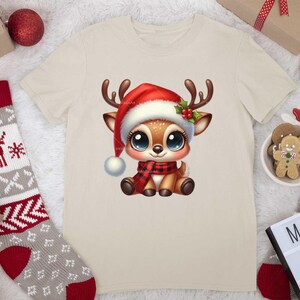 Op de afbeelding: Een beige T-shirt met een cartoon afbeelding van een rendier dat een rode kerstmanmuts en een rood-zwarte sjaal draagt. Het rendier heeft grote blauwe ogen en zit. Het T-shirt is een geweldig cadeau voor kerst.