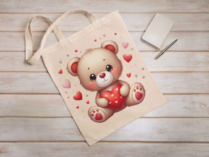 May include: A beige tote bag with a cartoon illustration of a brown teddy bear holding a red heart. The background is filled with small red and gray hearts.