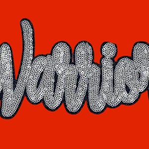 Pode incluir: Um remendo de lantejoulas prateadas com a palavra "Warriors" em um tipo de letra em negrito e estilizado. O remendo está em um fundo vermelho.