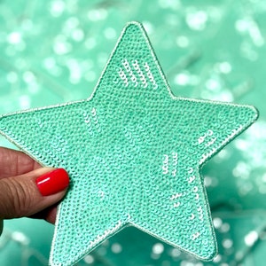 May include: A light green star-shaped patch covered in sequins. The sequins are a lighter shade of green with a white iridescent sheen.