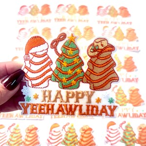 May include: An embroidered iron-on patch with a Christmas tree, a snowman, and a cowboy. The patch says "Happy Yeehawliday" in orange thread.