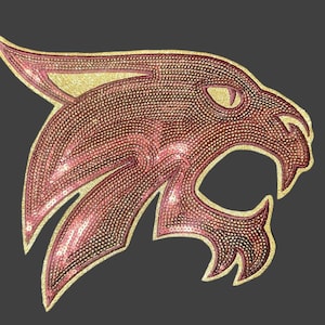 May include: A red and gold sequined patch of a wildcat head with an open mouth. The wildcat is facing the right side of the image.