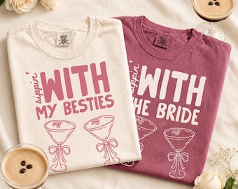 May include: Two crew neck t-shirts, one cream and one maroon, featuring the text Sippin with my besties and Sippin with the bride in bold lettering. Each shirt displays a graphic of two martini glasses with bows and coffee beans on top.