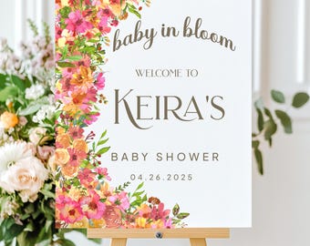 Puede incluir: Un cartel blanco para baby shower con un borde floral. El cartel dice "baby in bloom" y "Bienvenido a Keira's Baby Shower 04.26.2025".