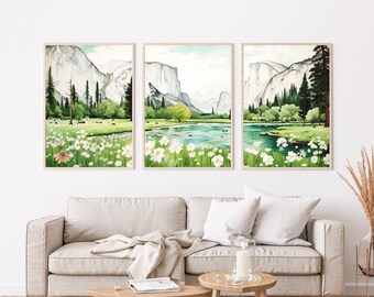 May include: Three watercolor paintings of a mountain landscape with a river and wildflowers. The paintings are framed and hung on a white wall above a light beige sofa.