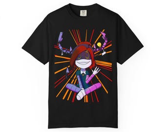 May include: Black t-shirt featuring a colorful cartoon character with red hair, a white face, and a green and purple outfit. The character is sitting cross-legged with arms raised. Orange and yellow lines radiate from behind the character.