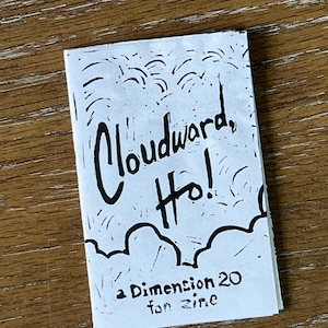 May include: A small, folded zine with the title "Cloudward, Ho!" in bold, black lettering. The cover features a hand-drawn illustration of clouds and the text "a Dimension 20 fan zine."