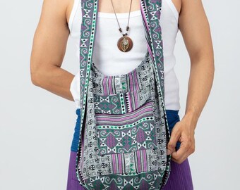 May include: A patterned shoulder bag with a long strap, featuring a design in shades of green, purple, and white. The bag has a pocket on the front and is worn over the shoulder. The bag is part of a collection of bohemian style accessories.